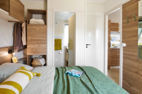Le mobil home TOSCANE 87.2 S est un modèle avec un bel espace de vie suite à l'agencement de la cuisine et du canapé TOSCANE 87.2 S 2026 : Chambre parentale